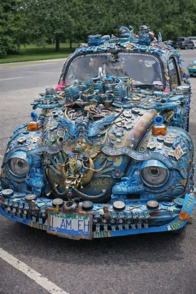 Heavily decorated blue Volkswagen Beetle art car covered in trinkets, charms, and sculptures