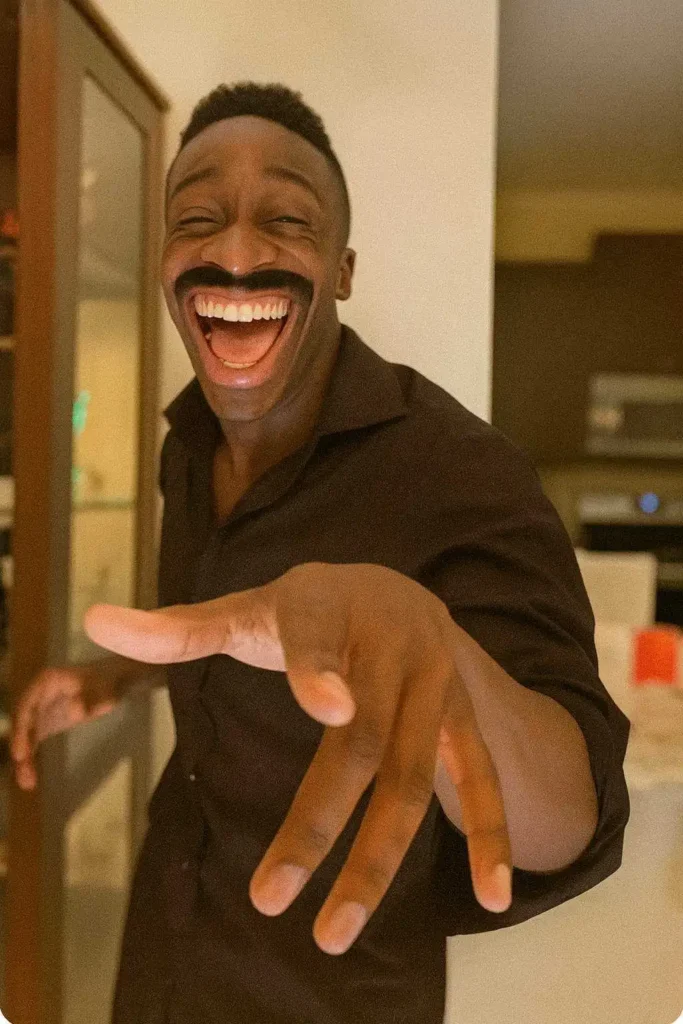 Laughing man pointing forward with exaggerated smile and joyful expression