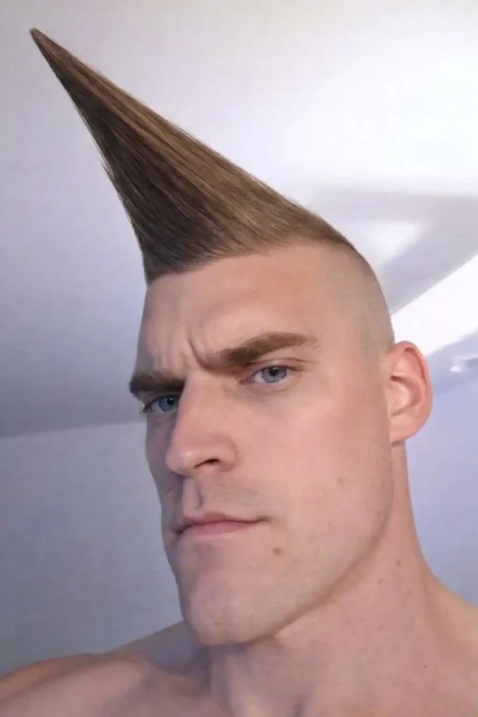 Man with an extreme cone-shaped mohawk haircut, shaved sides, and sharply styled hair pointing upward in a bold and unconventional hairstyle