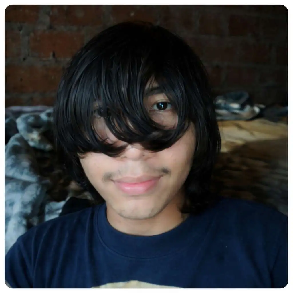 Person with long layered bangs covering most of the face, creating an emo-style haircut with a casual and slightly messy appearance