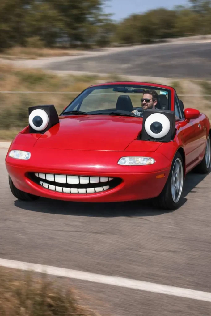 Red sports car with cartoon eyes and a wide smiling mouth driving on a highway
